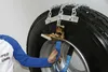 A person is shown attaching snow chains to a truck tire. Produktbild-Vorschau