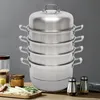 A multi-tiered stainless steel steamer pot set is displayed on a wooden surface with some ingredients and spice jars in the foreground. Podgląd zdjęcia produktu