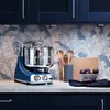 A blue Ankarsrum kitchen mixer sits on a countertop with a patterned backsplash and dark blue cabinets. Podgląd zdjęcia produktu