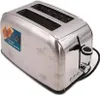 A stainless steel toaster with two slots is shown from a diagonal front-left perspective against a white background. A sticker with text and an image of toast is on the left side of the toaster. Anteprima dell’immagine prodotto