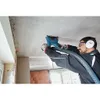 A man is using a Bosch angle grinder with a dust extraction hood attached to cut a groove in a concrete ceiling. Voir les images du produit