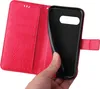 A hand is holding a red flip phone case open, revealing the black interior where a phone would be placed. Produktbild-Vorschau