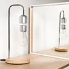 A levitating LED night light with a lightbulb design is shown on a wooden desk, with its reflection visible in a mirror. Náhled obrázku produktu