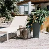 A sun lounger and a plant pot are placed on a gravel patio next to a building. Voir les images du produit