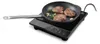 A black induction cooker with a frying pan containing three steaks, garlic, and rosemary on top. Náhled obrázku produktu