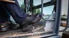 A person's feet wearing safety shoes inside a construction vehicle. Produktbild-Vorschau