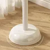 Close-up of the white base of a floor lamp or similar item, standing on a wooden floor with sheer curtains in the background. Produktbild-Vorschau