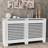 A white radiator cover with horizontal slats is displayed in a room with a concrete wall and wooden floor. Decorative items are placed on top of the cover. Náhľad obrázku produktu
