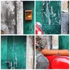 A collage of four close-up images showing details of a red scooter parked next to a weathered green door and a textured stone wall. One image shows a vintage-style mailbox. Produktbild-Vorschau