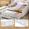 A white bed with storage drawers and a pull-out guest bed, set in a room with a window and a shelf unit above the headboard. Produktbild-Vorschau