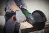 A person is using an angle grinder to cut a metal pipe, with sparks flying. Produktbild-Vorschau