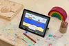A tablet is shown on a desk with drawing supplies, a wooden toy, and a wooden rainbow. Produktbild-Vorschau
