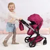 A young girl is pushing a doll stroller in a decorated room. Produktbild-Vorschau