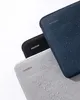 Three laptop sleeves are stacked on a white background, with water droplets on two of them. Produktbild-Vorschau