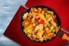 A close-up overhead shot of a pan filled with mixed vegetables, placed on a red cloth on a blue wooden table. Náhľad obrázku produktu