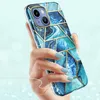 A hand holding an iPhone 14 Plus with a blue and gold geometric case. Podgląd zdjęcia produktu