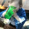 A baby drinking from a green cup. Produktbild-Vorschau