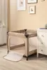 A baby playpen is set up in a room with a dresser and framed pictures on the wall. Produktbild-Vorschau