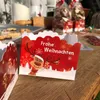 Christmas-themed treat bags with a reindeer design are placed on a wooden table, with cookies and baking supplies in the background. Produktbild-Vorschau