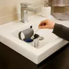 A hand is placing a toothbrush into a sink organizer in a bathroom sink. Podgląd zdjęcia produktu