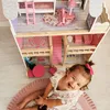 A baby girl is playing with a dollhouse. Voir les images du produit