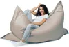 A woman is sitting comfortably on a large, light gray beanbag chair. Produktbild-Vorschau