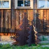 Two metal Christmas trees with star cutouts stand in front of a rustic wooden wall and stone foundation. Voir les images du produit