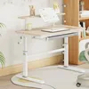 A child's adjustable desk with a shelf and a book on it, set in a room with a bookshelf in the background. Produktbild-Vorschau