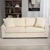A cream-colored corduroy sofa with three seat cushions and three back cushions, along with two decorative pillows, is shown in a living room setting. A wooden bookshelf with decorative items is visible in the background. Podgląd zdjęcia produktu