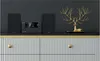A stereo system with two speakers and a central unit is displayed on a dark shelf above a white ribbed cabinet with gold knobs. Anteprima dell’immagine prodotto