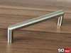 A silver cabinet handle lies on a wooden surface. Produktbild-Vorschau
