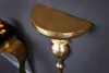 A close-up shot of a gold-colored wall console mounted on a dark gray wall. Produktbild-Vorschau