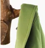 A close-up of a green fabric item hanging on a wooden branch hook. Produktbild-Vorschau