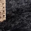 A close-up view of a black shaggy rug with a woven basket on the left side. Anteprima dell’immagine prodotto