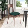 A dark green seat cushion is placed on a wooden chair in a dining room setting. Náhľad obrázku produktu