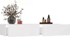 A white floating shelf with two drawers, decorated with a vase of flowers and two bottles on the left, and a tray with three bottles on the right. Produktbild-Vorschau