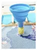 A blue funnel is being used to pour yellow beads into a small glass bottle. The background shows a diamond painting canvas. Produktbild-Vorschau