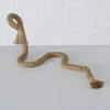 A thick jute rope is laid out on a white surface with a white brick wall in the background. The rope is bent into a serpentine shape, with a loop and tassel at one end and frayed ends at the other. Produktbild-Vorschau