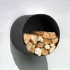 A black, round, wall-mounted firewood rack filled with logs, attached to a textured white wall. Produktbild-Vorschau