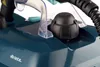 Close-up view of the top of a teal steam cleaner base, showing a black cap and a clear plastic handle support. Anteprima dell’immagine prodotto