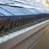 Close-up of a black mesh gutter guard installed on a house gutter, with roof shingles visible in the background. Produktbild-Vorschau