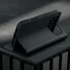 A black leather iPhone case is shown standing upright on a dark, textured surface. Anteprima dell’immagine prodotto