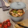 A Dutch oven filled with salmon, potatoes, and green beans sits on a wooden table, with tomatoes and potatoes scattered around. Náhľad obrázku produktu