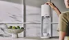 A person is using a SodaStream machine on a kitchen counter next to a bowl of limes. Produktbild-Vorschau