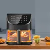 An air fryer is shown on a wooden countertop with food in the foreground and background. Produktbild-Vorschau