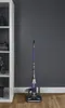 A vacuum cleaner is standing on a wooden floor next to a white shelf. Produktbild-Vorschau