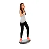 A young woman is standing on a balance board. Produktbild-Vorschau