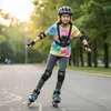 A young girl is rollerblading on a paved path in a park. Náhľad obrázku produktu