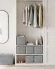 A closet with hanging clothes and storage boxes. Produktbild-Vorschau