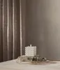 A white bubble candle with a lit LED flame sits on a stone base, surrounded by dried flowers and eucalyptus branches, with a textured brown curtain in the background. Podgląd zdjęcia produktu